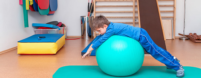 Child stretching on a yoga ball in a Physical Therapy gym