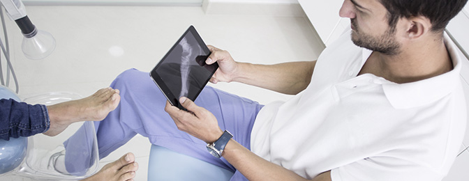 Man looking an a foot x-ray on a tablet device