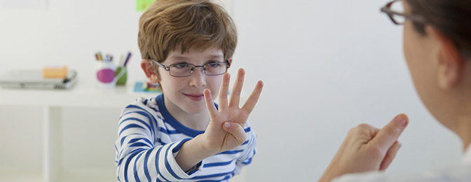 Young child with glasses holding up four fingers